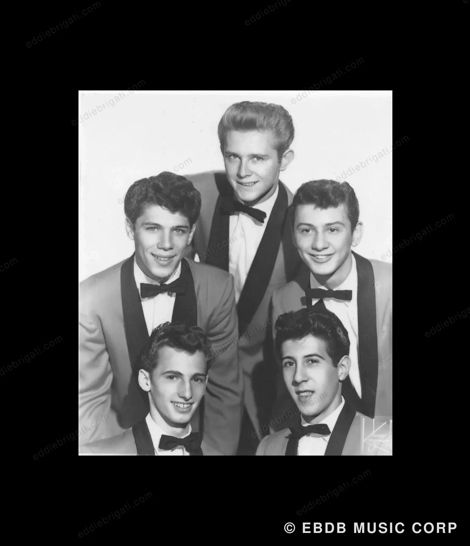 A black-and-white group photograph of five young men in dinner jackets and bow ties, framed and mounted on black.